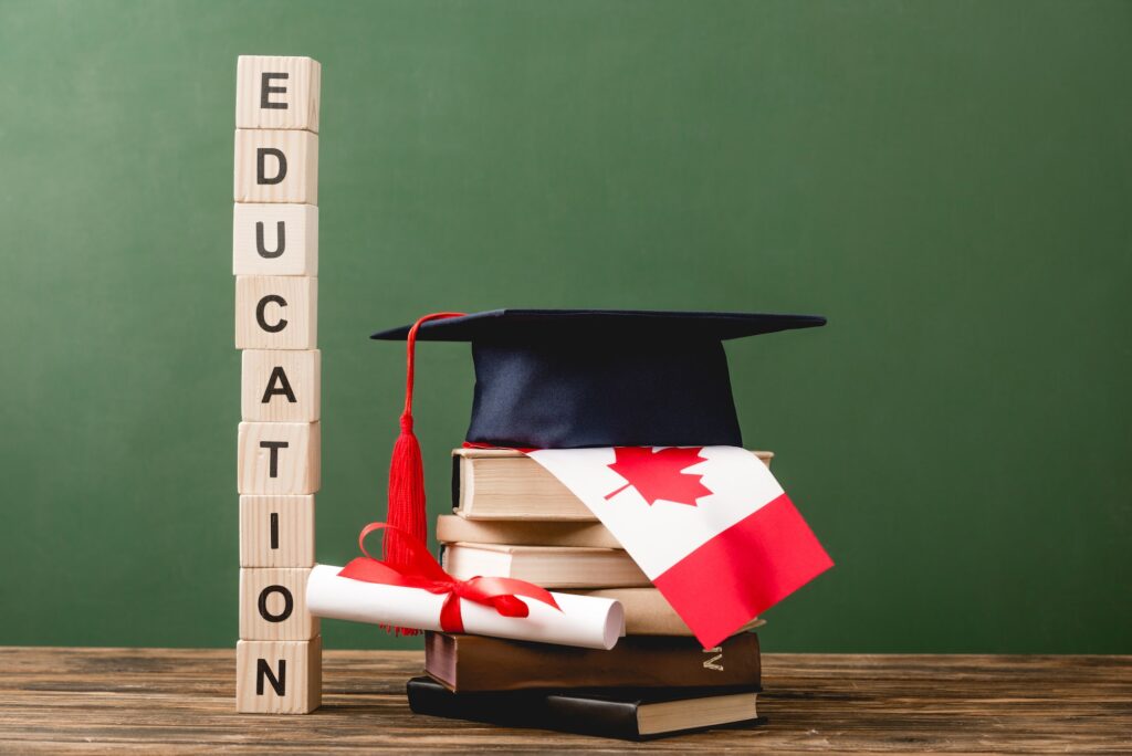 wooden blocks with letters, diploma, books, academic cap and canadian flag on wooden surface